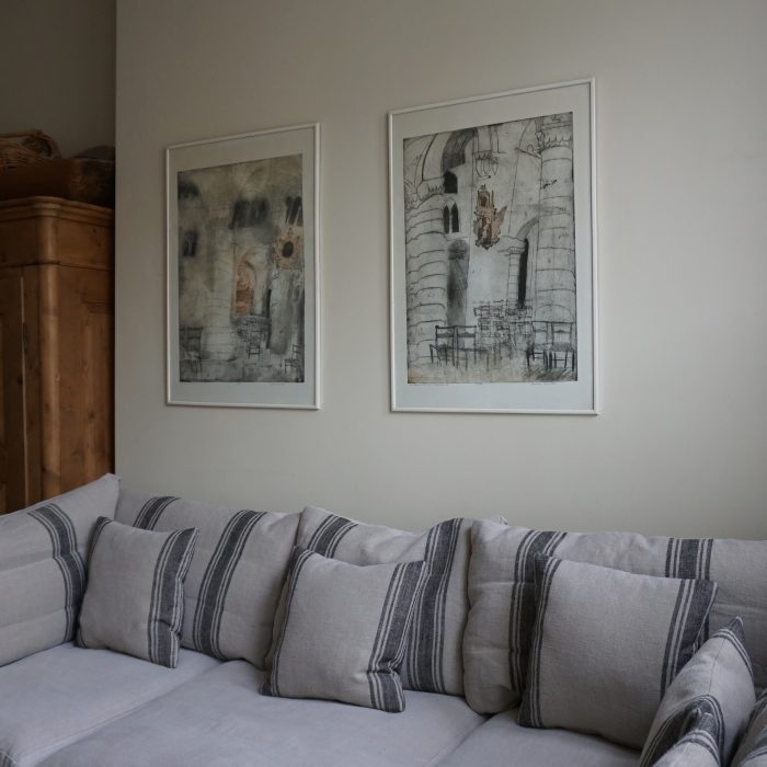 A sofa with cushions and 2 drawings above